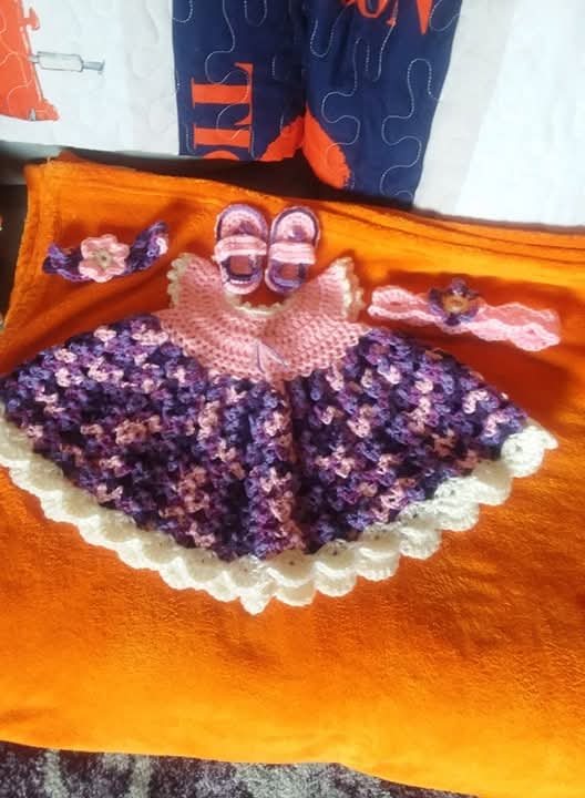 A baby set: a purple and pink crochet dress with booties and a headband