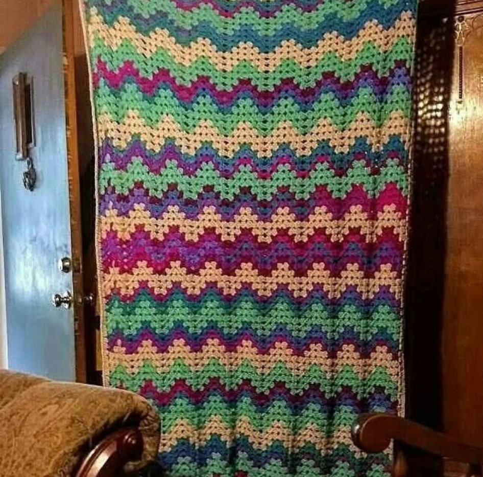 A zigzag blanket in green, purple, yellow and pink