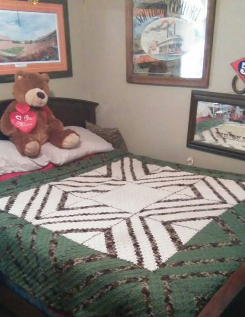 A green and white bed blanket in a geometric pattern