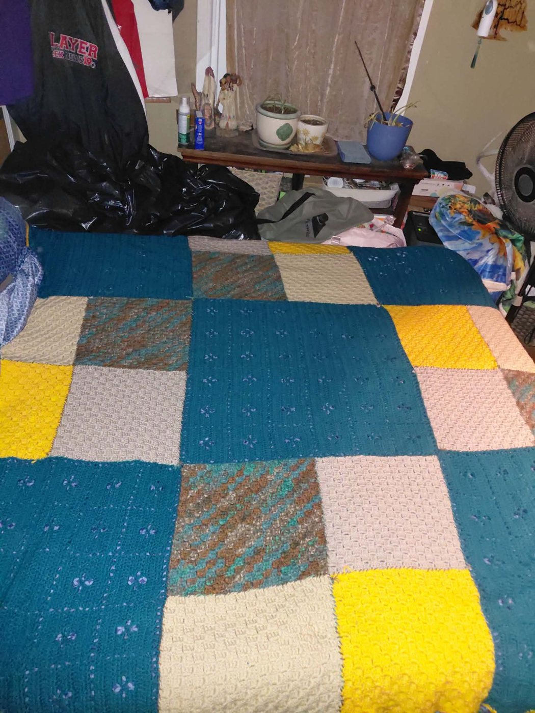 A patchwork bed blanket in teal, yellow and cream squares