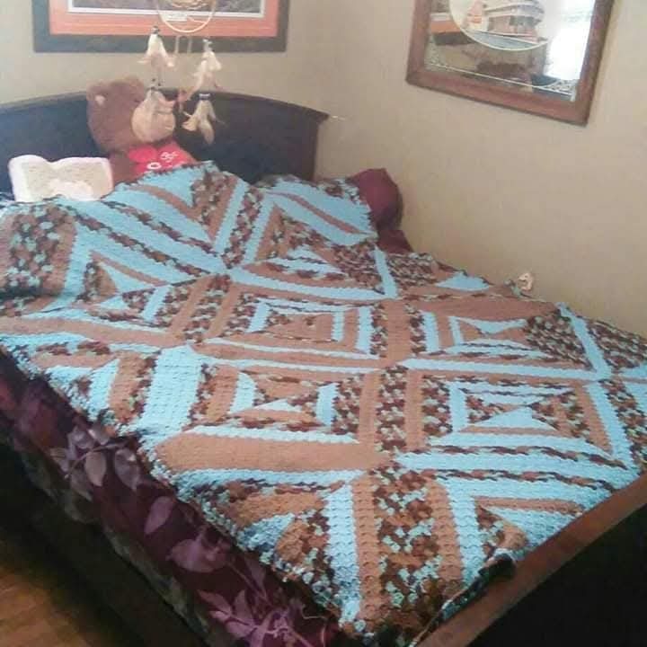 A bed blanket in brown and light blue geometric squares