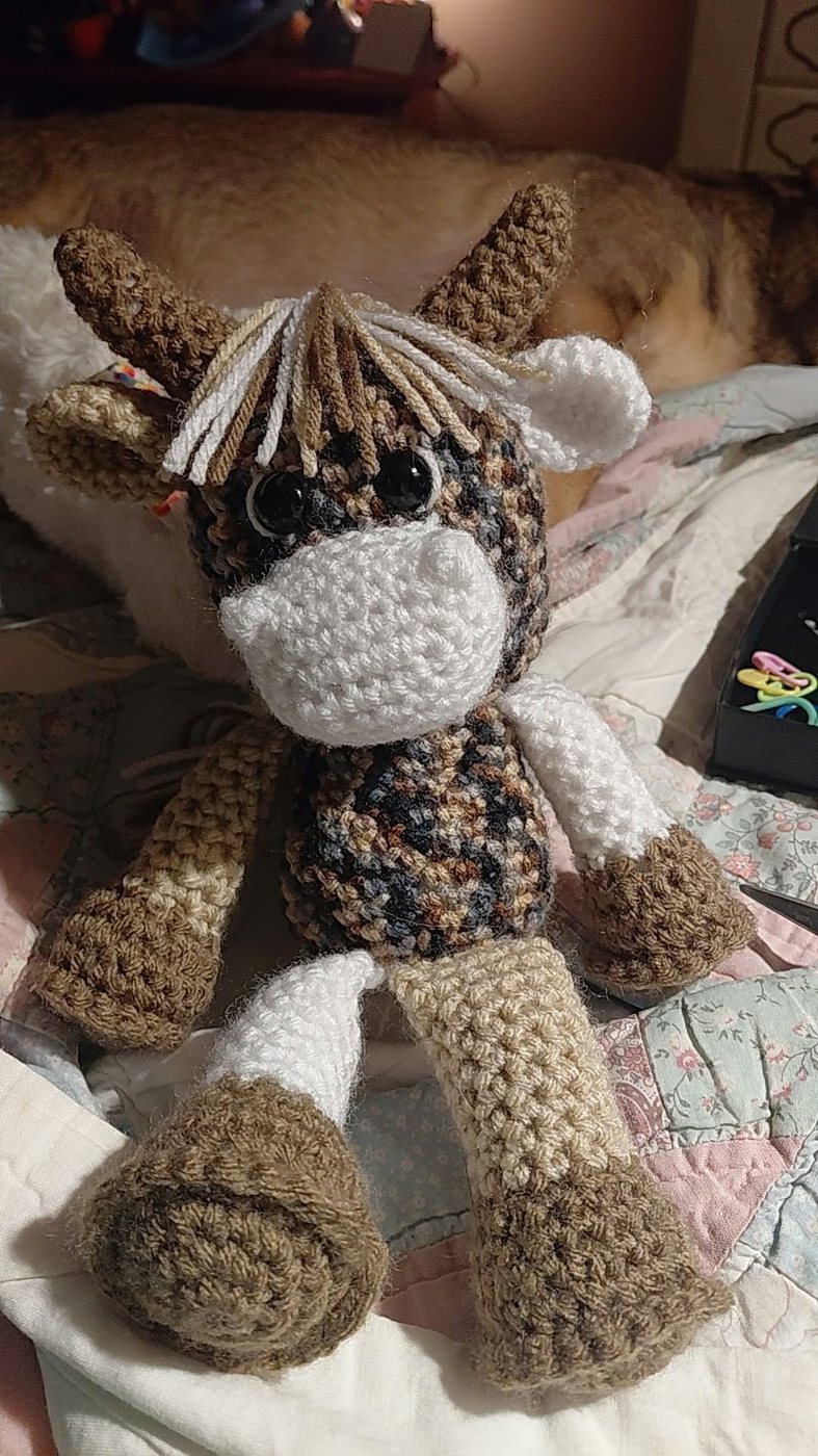 A crochet highland cow in brown tweed yarn