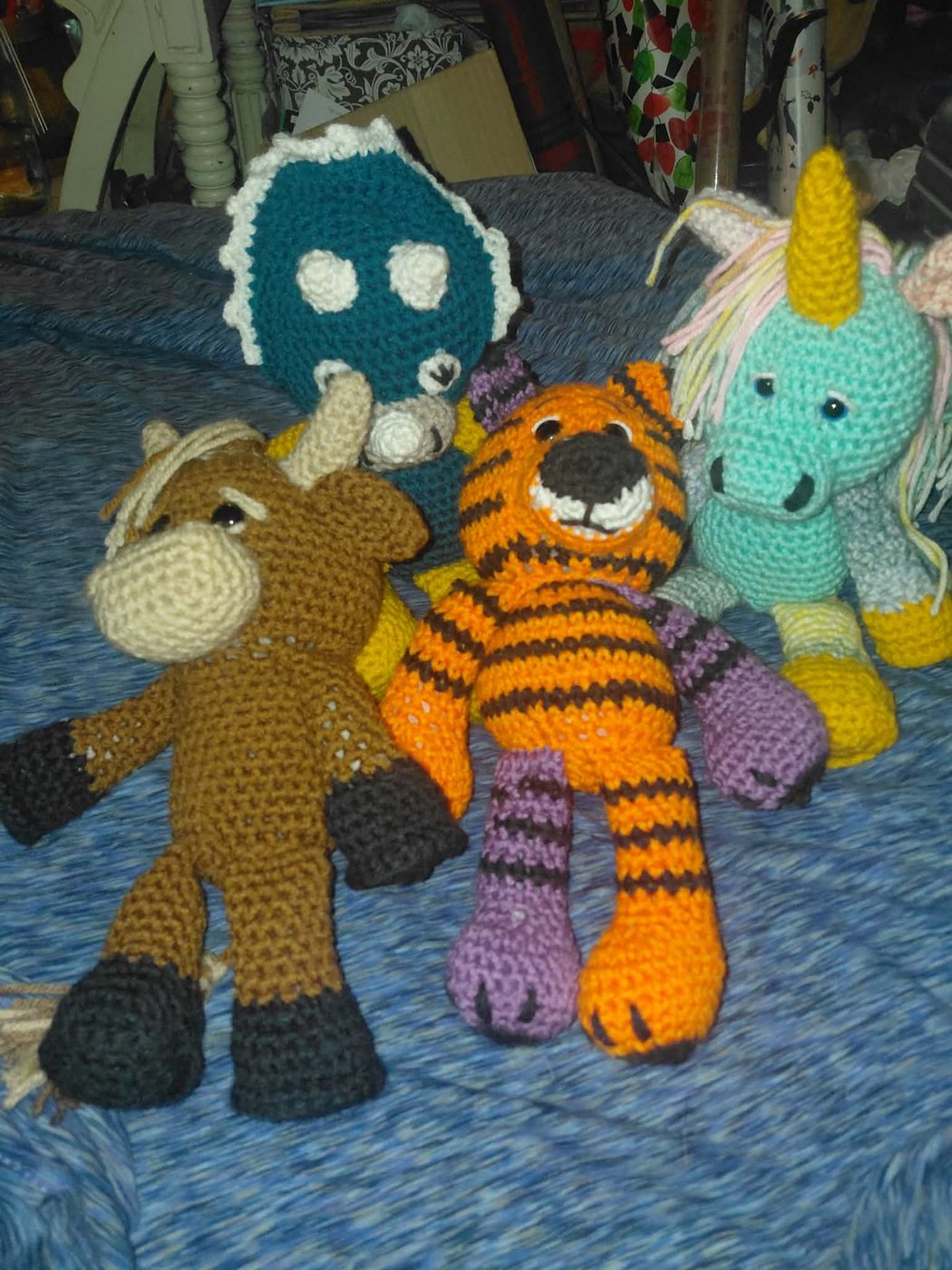 A crochet tiger and dinosaur with a highland cow and a unicorn